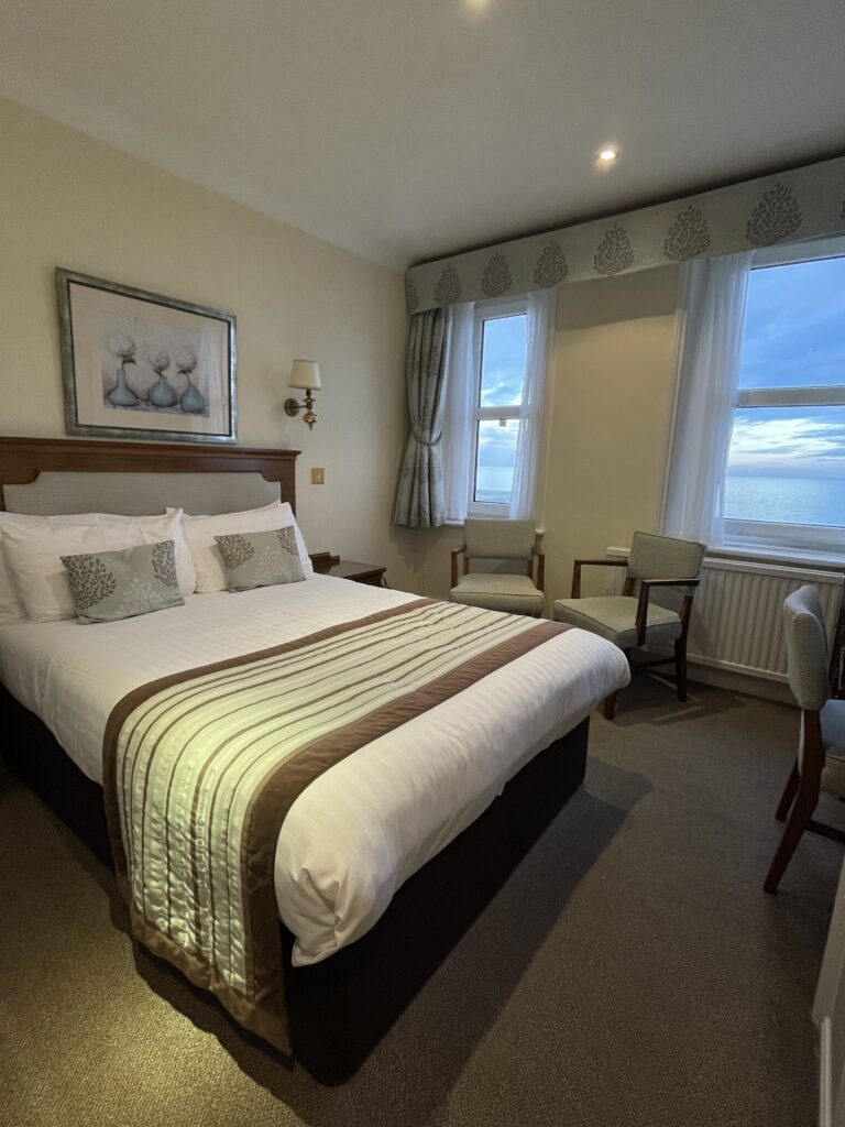 A double bed in a room over looking the blue sea and sky