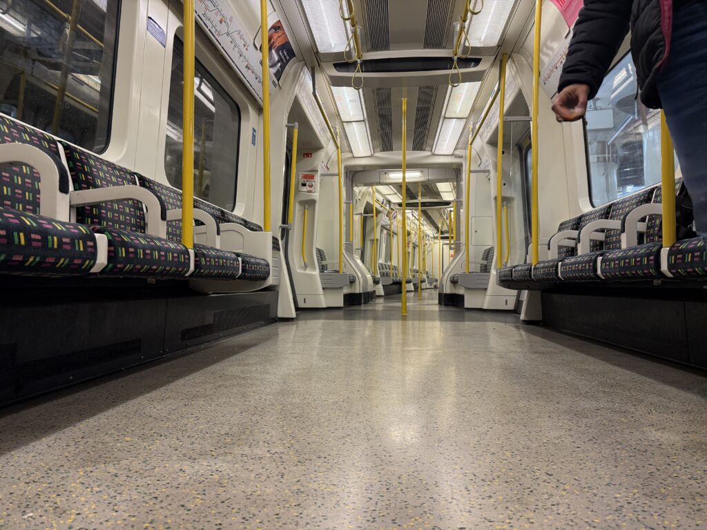 An empty Tube carriage, with seats down the side of the train and yellow hand rails.